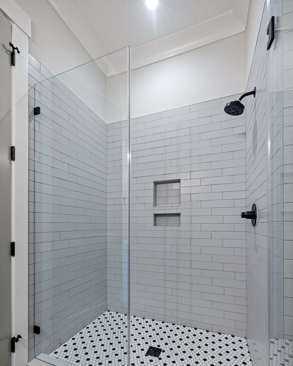 A tiled wet room with a walk-in shower and a linear floor drain